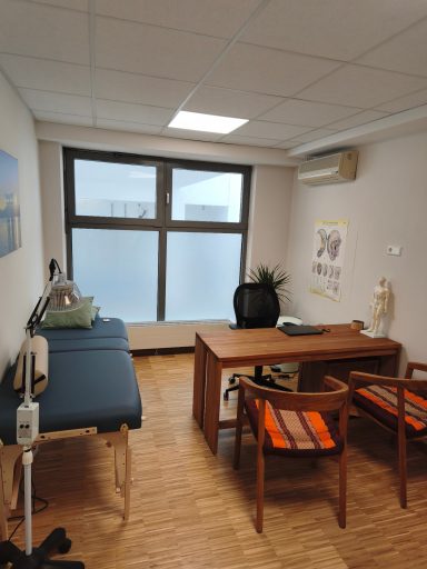 Behandlungsraum mit Liege, Tisch, Stühlen und Fenster für Tageslicht.