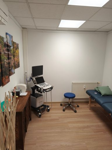 Ärztlicher Behandlungsraum mit einem Untersuchungsstuhl und medizinischer Ausstattung.